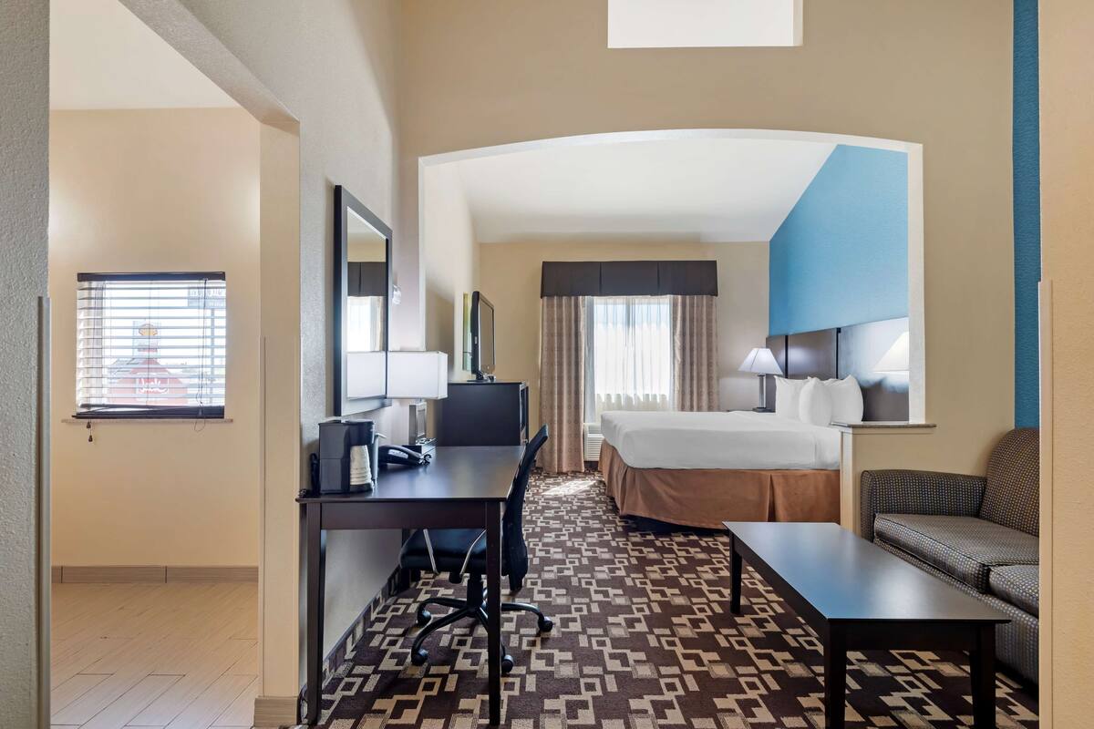 Une chambre d’hôtel avec un lit, un bureau, une chaise et un canapé.