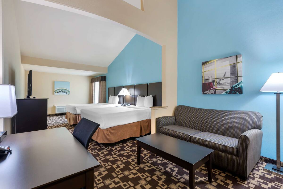 Une chambre d’hôtel avec un lit, un canapé, un bureau et une lampe.