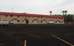 A motel with a red roof and beige walls, featuring a parking lot with several vehicles. - Quality Inn Del Rio (Del Rio)