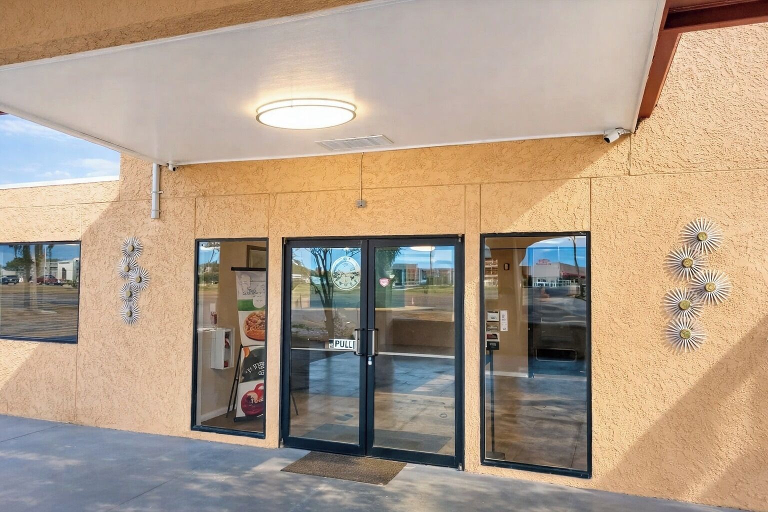 A building entrance with a glass door, a pull sign, and decorative wall elements.