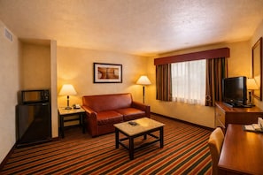 A hotel room with a sofa, a coffee table, a television, a microwave, and a lamp. - Quality Inn Del Rio (Del Rio)