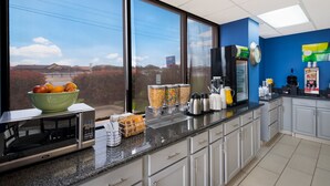 A modern kitchen with a large window, a microwave, a coffee machine, and various food containers. - Quality Inn & Suites Round Rock - Austin North (Round Rock)