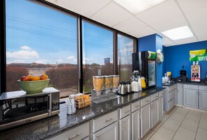 A modern kitchen with a large window, a microwave, a coffee machine, and various food containers.