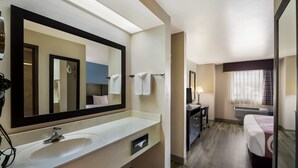 A hotel bathroom with a large mirror, a sink, and a towel rack. - Quality Inn & Suites Round Rock - Austin North (Round Rock)