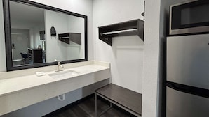 Une salle de bain moderne avec un grand miroir, un lavabo, une serviette et un réfrigérateur encastré.