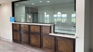 Un espace d’accueil doté d’une cloison en verre, d’un décor mural en panneaux de bois et d’un panneau indiquant les avantages liés à l’adhésion.