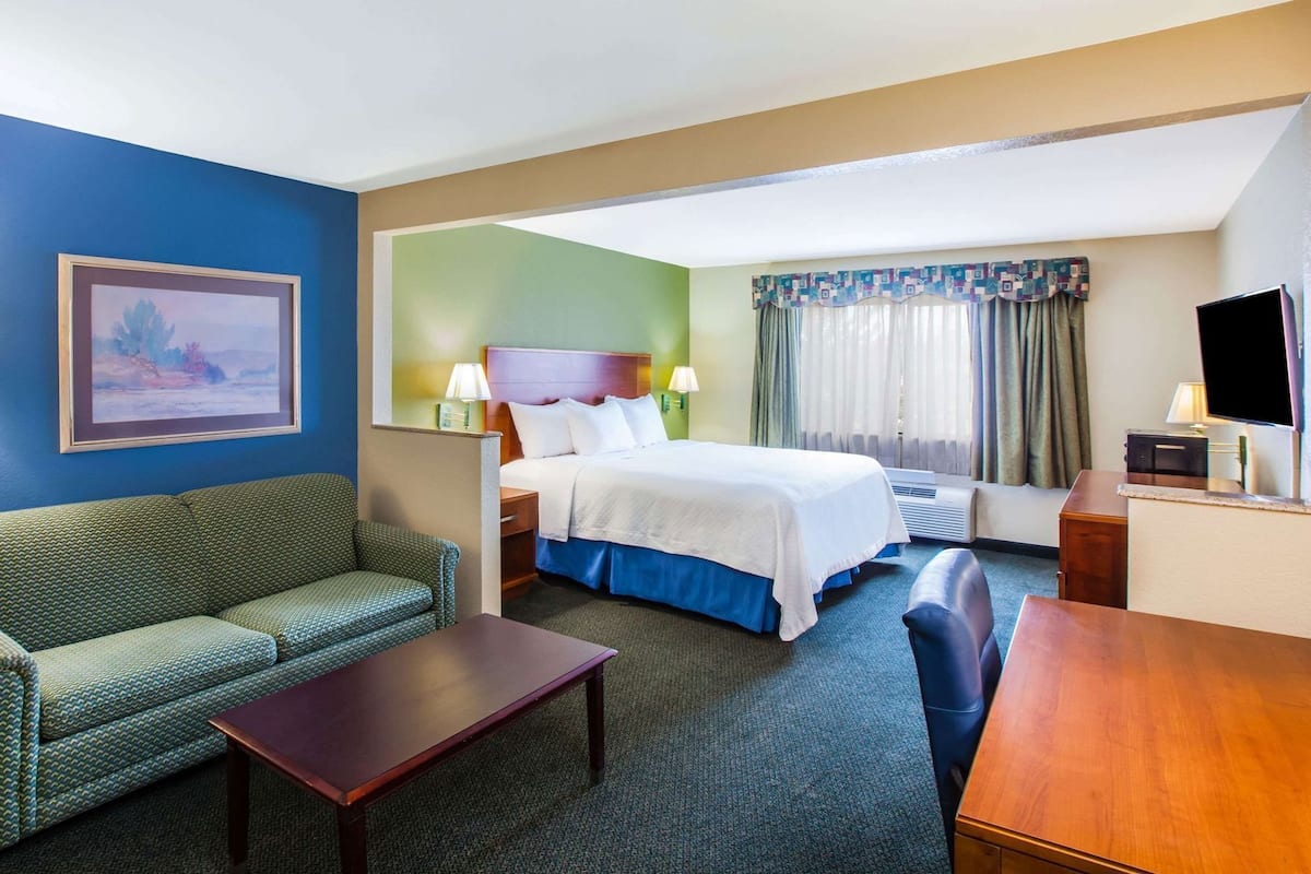 A hotel room with a bed, a sofa, a desk, and a TV.