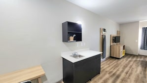 A modern kitchen with a sink, a wooden cabinet, and a built-in microwave. - Days Inn & Suites by Wyndham Corpus Christi Central (Corpus Christi)