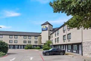 Edificio de Days Inn & Suites con estacionamiento, un automóvil negro estacionado y cielo azul despejado.