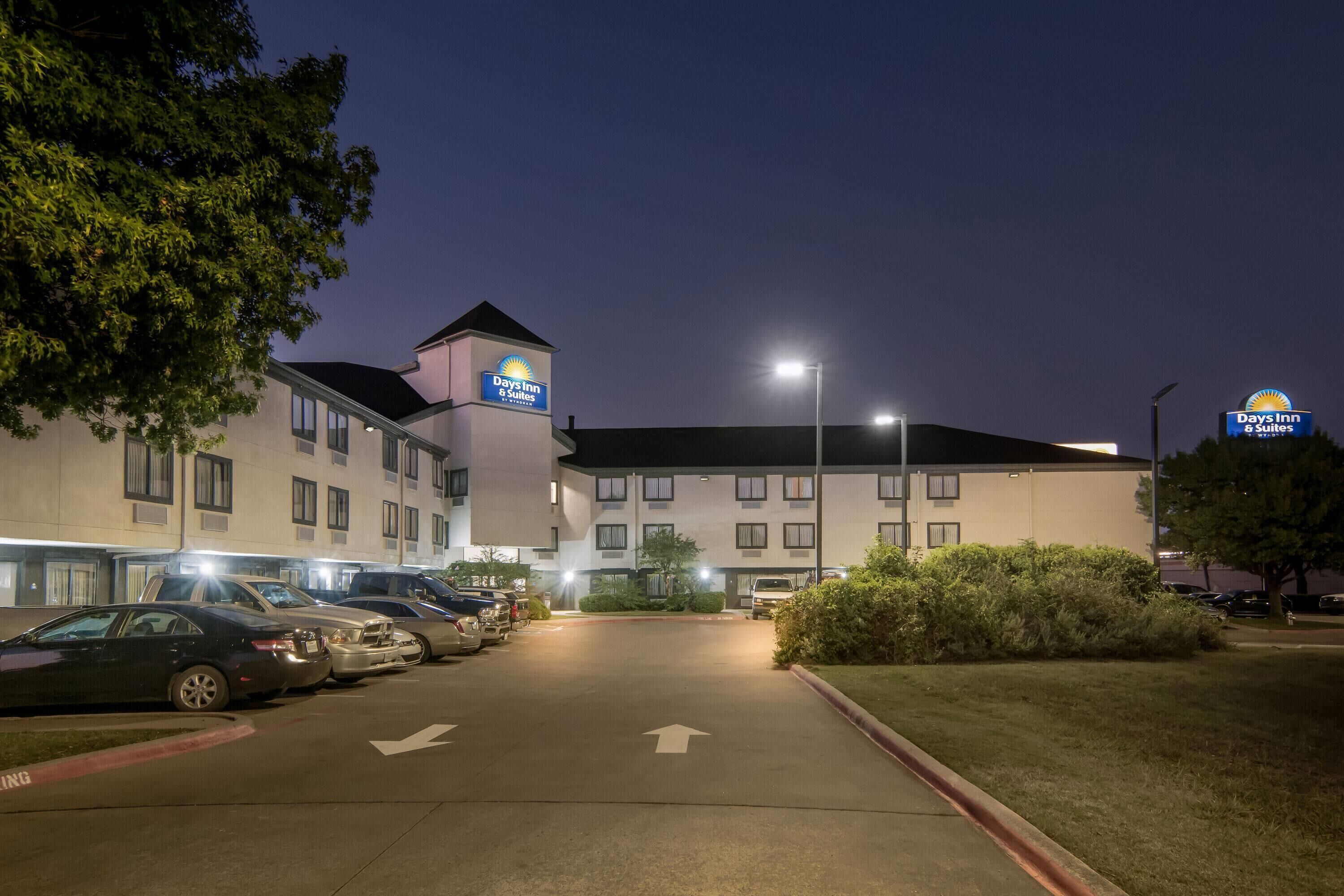 A Days Inn & Suites hotel with a parking lot and a building with multiple windows and a tower.