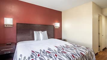 A hotel room with a bed, bedside tables, and wall-mounted lights.