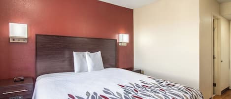 A hotel room with a bed, bedside tables, and wall-mounted lights.