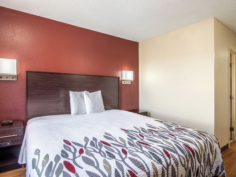 A hotel room with a bed, bedside tables, and wall-mounted lights.