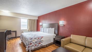Ein Hotelzimmer mit Bett, Schreibtisch, Stuhl, Sofa und Fernseher.