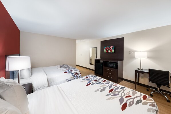 A hotel room with two beds, a desk, a chair, a TV, and a lamp. - Red Roof Inn El Paso West (El Paso)