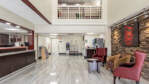 Un hall de hotel con una recepción, un cajero automático, una zona de estar con sillas y un letrero de Red Roof Inn.