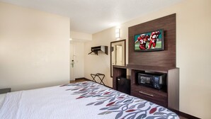 A hotel room with a bed, a flat-screen TV mounted on the wall, a microwave, and a small seating area with a chair. - Red Roof Inn El Paso West (El Paso)