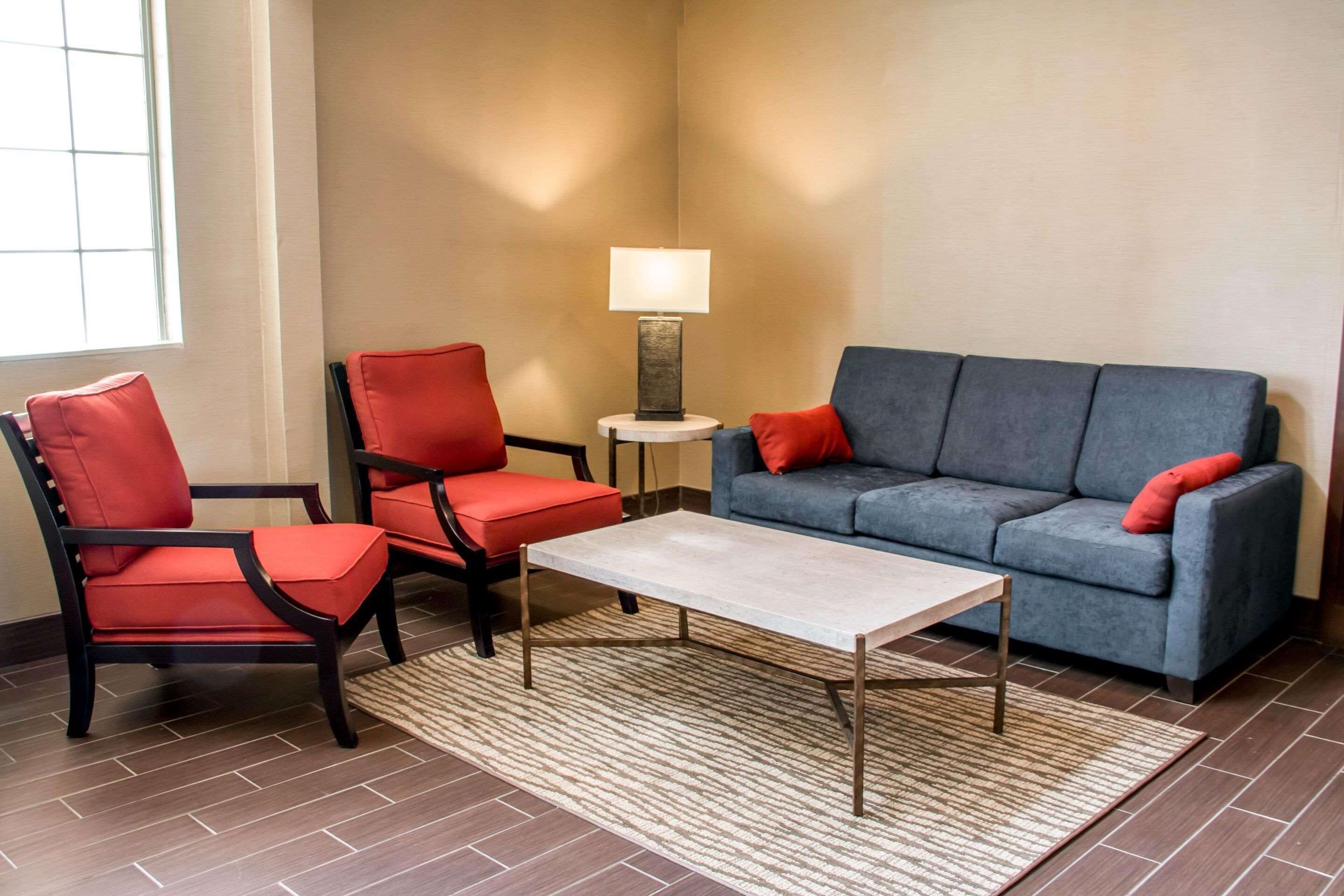 Uma sala de estar com um sofá, duas poltronas, uma mesa de centro e um abajur.