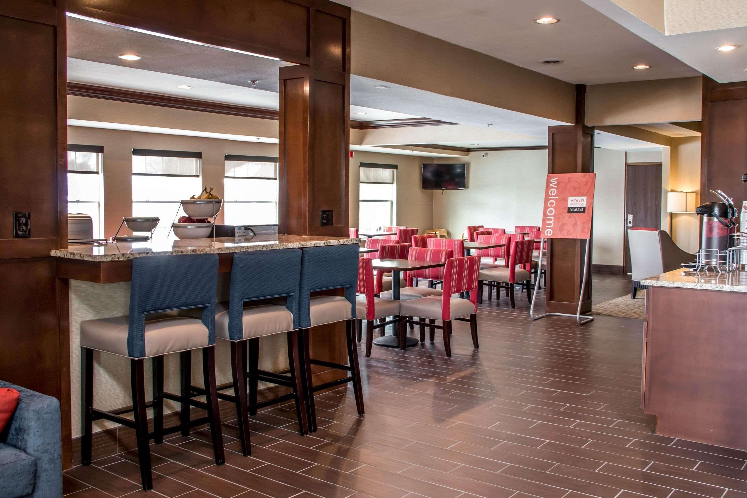 Un vestíbulo de hotel con zona de bar, varias mesas de comedor y sillas.