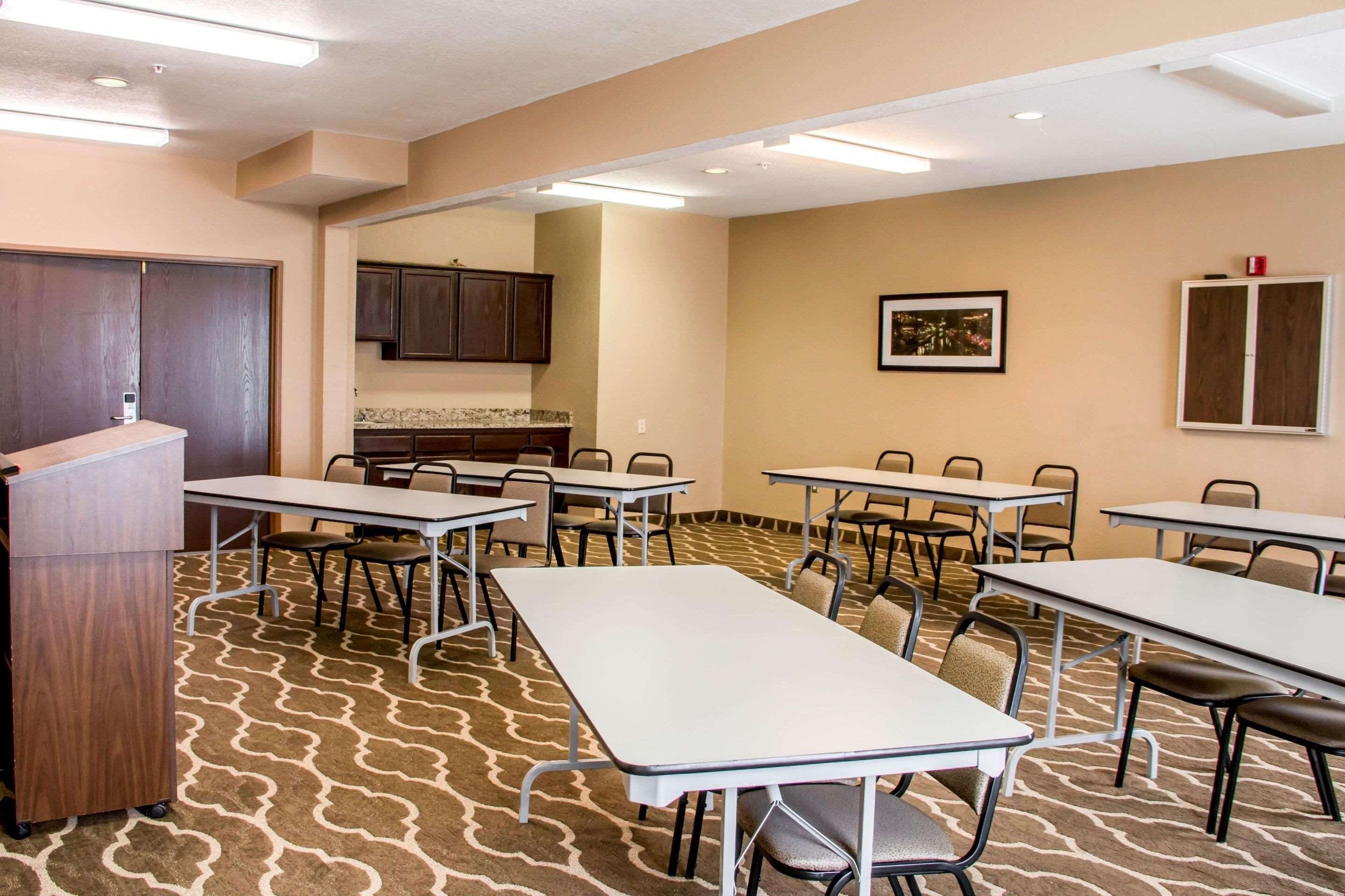 Un salón de conferencias con mesas, sillas, un atril y una kitchenette.