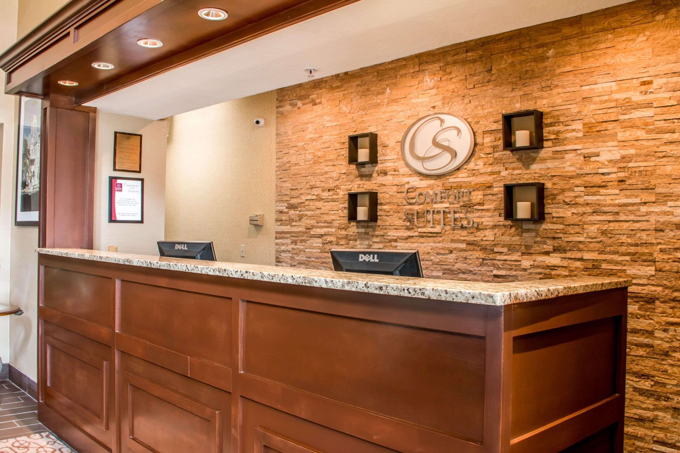 A reception desk with a stone wall backdrop, a logo, and two Dell computers.