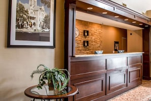 A reception area with a stone wall, a framed photo, a reception desk, and a small table with a plant.
