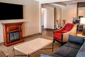 A living room with a fireplace, a sofa, a coffee table, and a TV mounted on the wall.