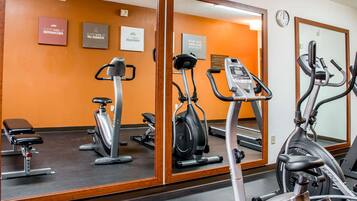 Une salle de sport équipée de matériel d’exercice, d’un banc et ornée de citations motivantes sur les murs.
