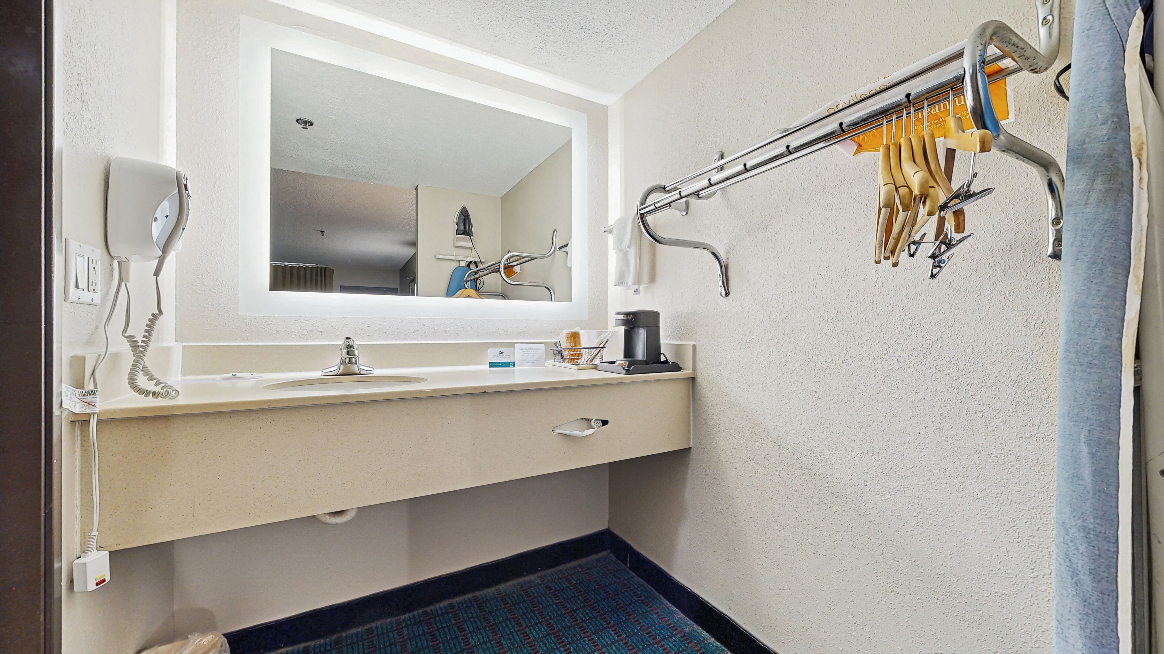 Une salle de bain équipée d’un lavabo, d’un miroir, d’un porte-serviettes et d’une machine à café.