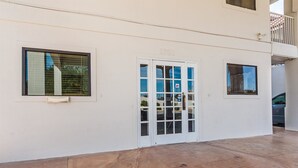 Fachada de un edificio con una puerta blanca, dos ventanas y un balcón.
