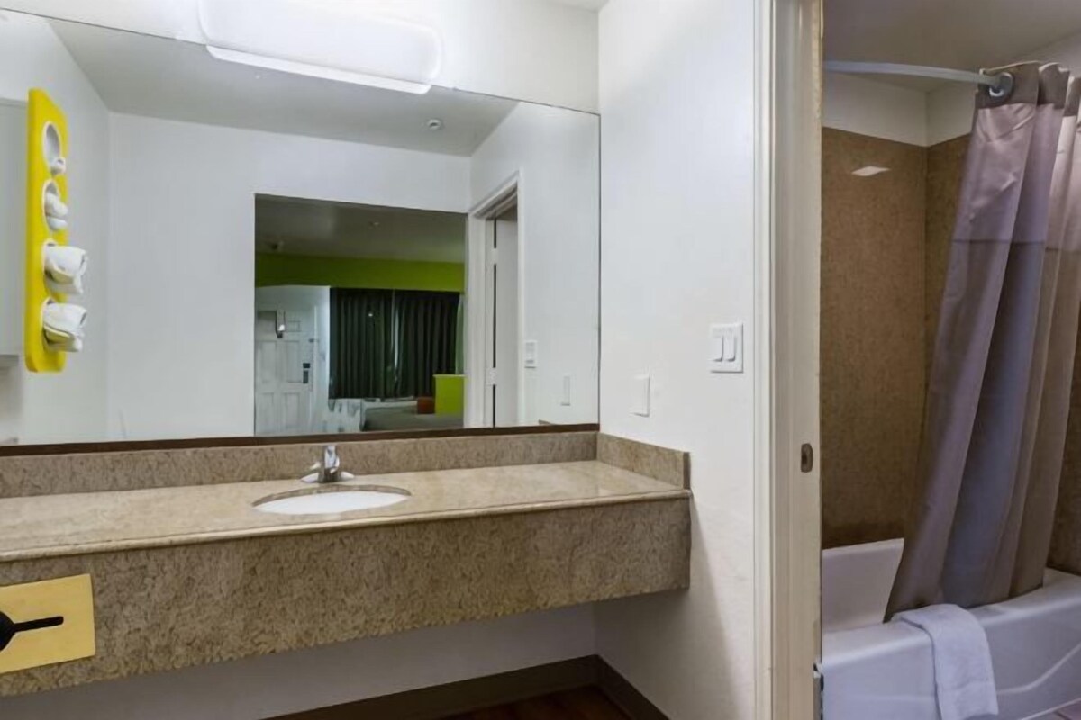 A bathroom with a sink, mirror, and shower curtain.