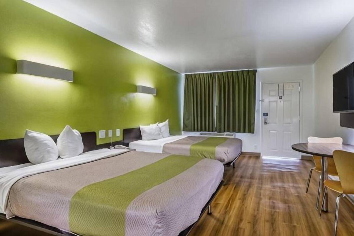 A hotel room with two beds, a dining table, and a TV.