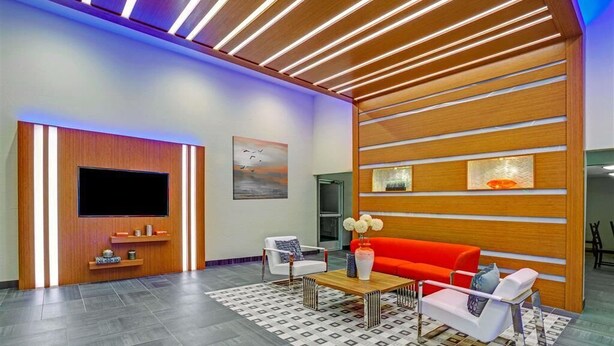 A modern living room with a flat-screen TV, a red sofa, a coffee table, and a patterned rug.