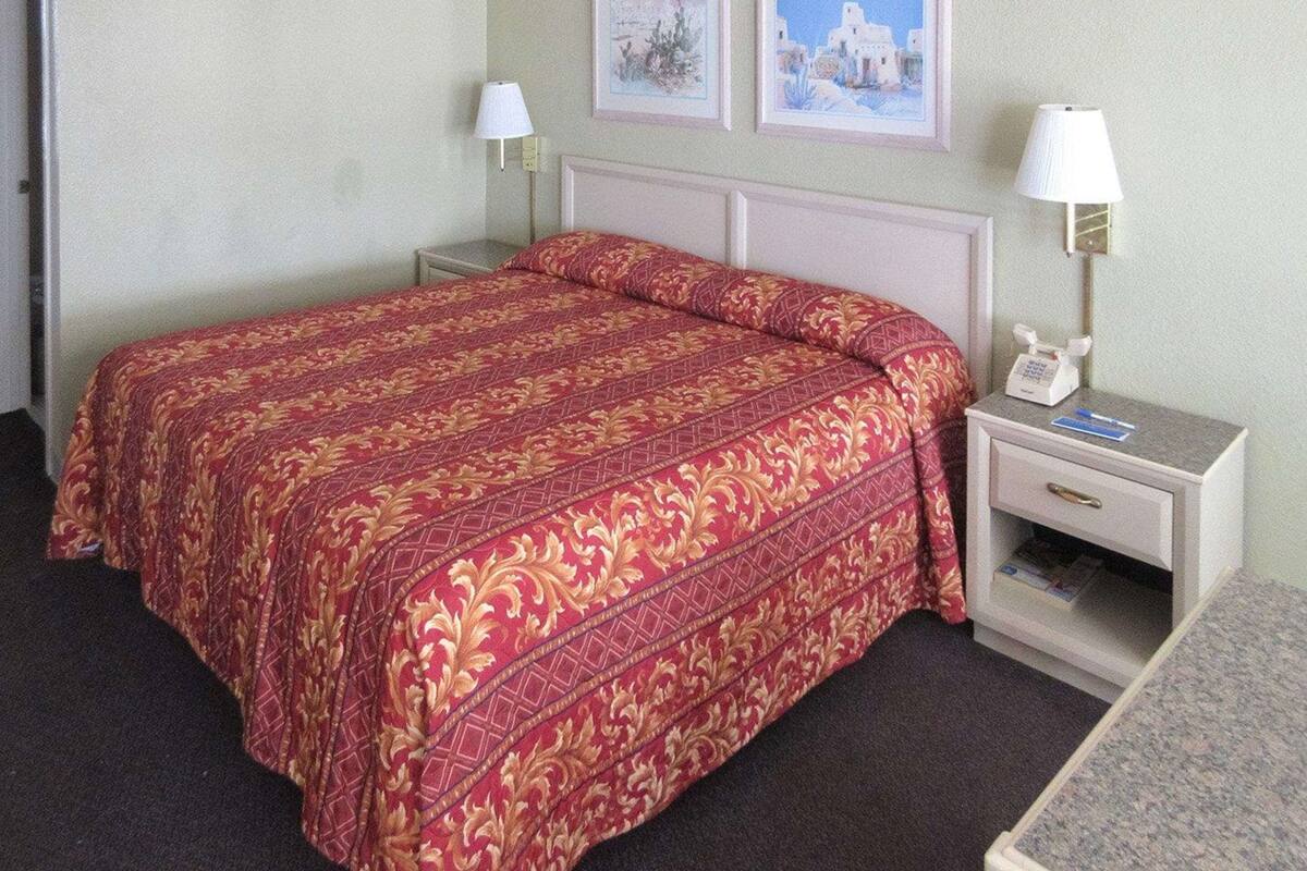 A hotel room with a large bed, two bedside tables with lamps, and two framed pictures on the wall.
