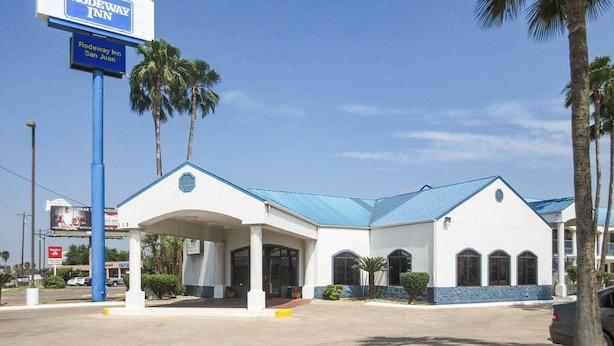 A Rodeway Inn with a covered entrance, palm trees, and a clear blue sky. - Rodeway Inn San Juan (San Juan)