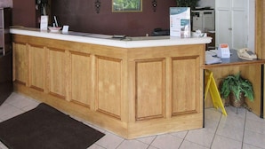 A reception area with a wooden counter, a framed picture on the wall, and a sign about rewards. - Rodeway Inn San Juan (San Juan)