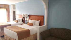 A hotel room with two beds, a sofa, and a large window with curtains. - Coratel Inn & Suites by Jasper New Braunfels IH-35 EXT 189 (New Braunfels)
