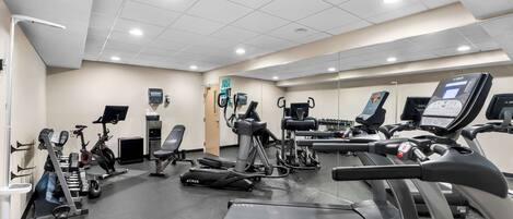 Un gimnasio con diversos equipos de ejercicio, incluyendo cintas de correr, bicicletas estáticas y máquinas de pesas.