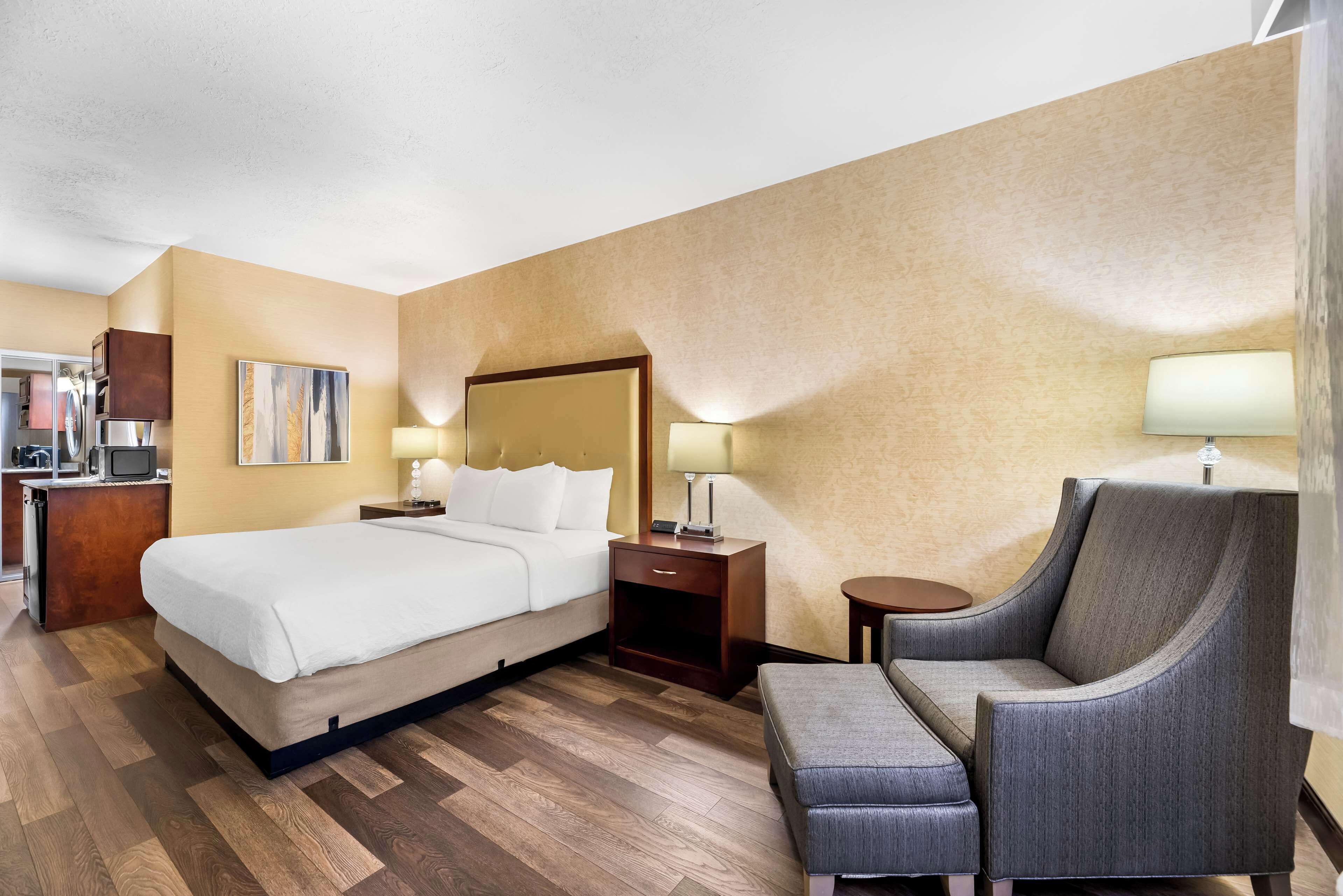 Une chambre d’hôtel comprenant un lit, des tables de chevet, une chaise et un bureau avec une lampe.