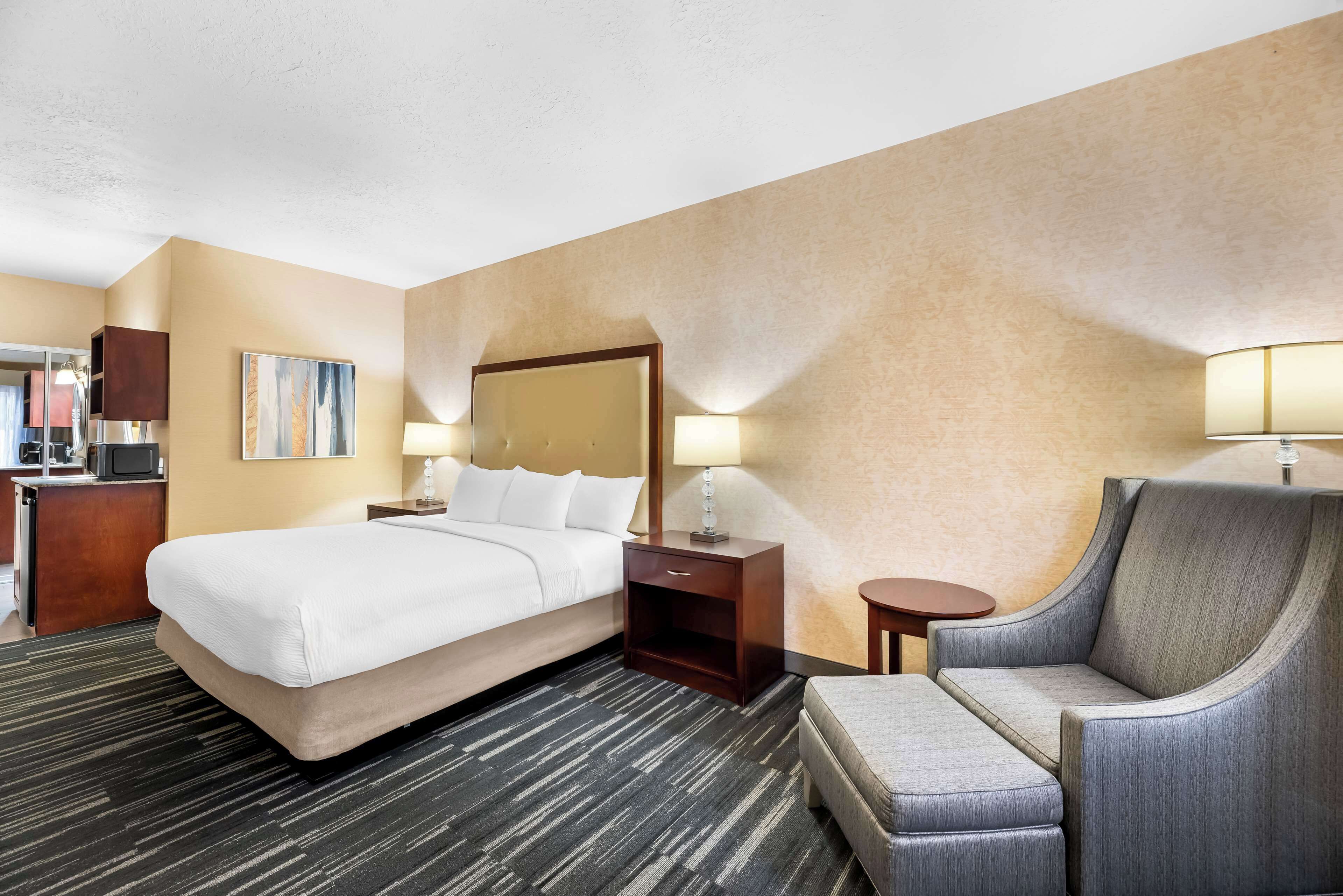 Une chambre d’hôtel avec un grand lit, un bureau, une chaise et un téléviseur.