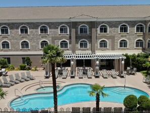 A hotel with a swimming pool, outdoor seating, and a covered patio area.
