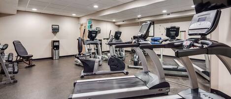 Une salle de sport équipée de tapis de course, de vélos elliptiques et de matériel de musculation.