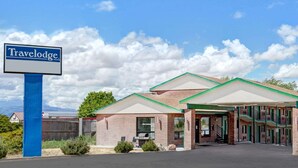 A Travelodge hotel with a brick facade, green awnings, and a clear blue sky. - Travelodge by Wyndham Cedar City (Cedar City)