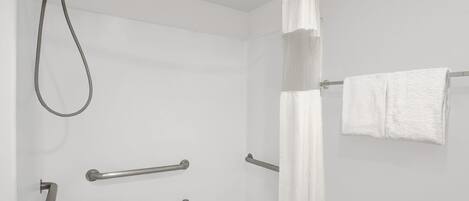 Un baño moderno con ducha, barras de apoyo y un perchero para toallas.
