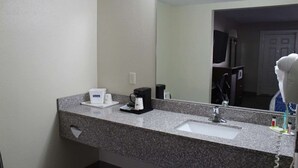 A hotel bathroom with a granite countertop, a sink, a coffee maker, and a hairdryer. - Travelodge by Wyndham Cedar City (Cedar City)