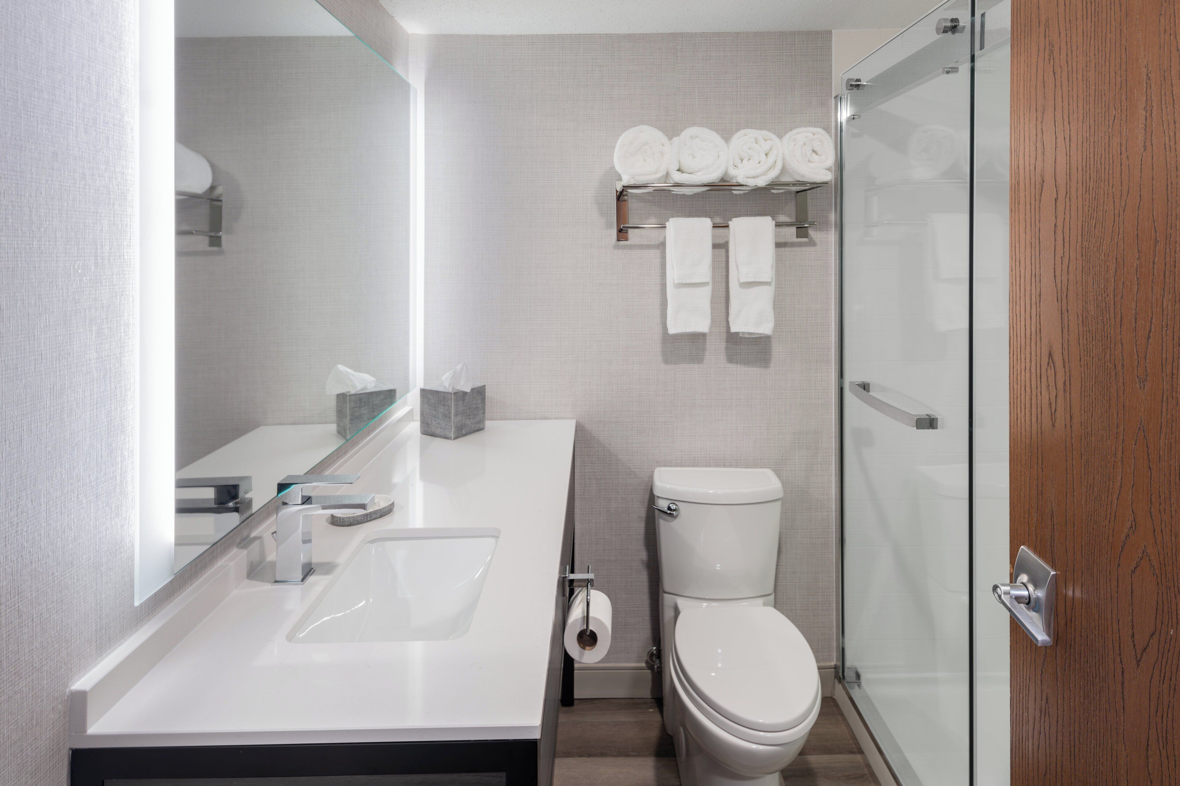 A modern bathroom with a white sink, toilet, and glass shower enclosure.