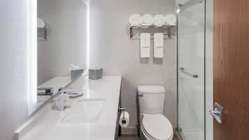 Een moderne badkamer met een wit wastafelmeubel, toilet en douchecabine met glazen wanden.