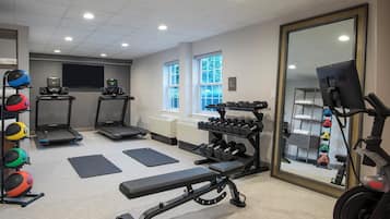 A gym with treadmills, a bench, dumbbells, and exercise balls.
