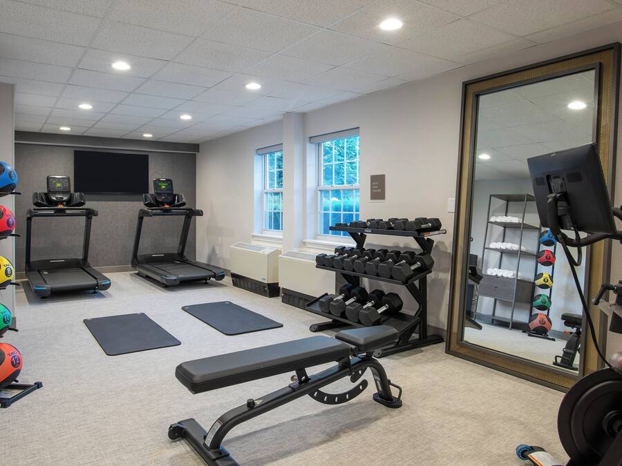 A gym with treadmills, a bench, dumbbells, and exercise balls.