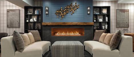 Una sala de estar moderna con chimenea, dos sofás y estanterías decorativas.